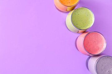 Glasses of different fresh smoothie on lilac background