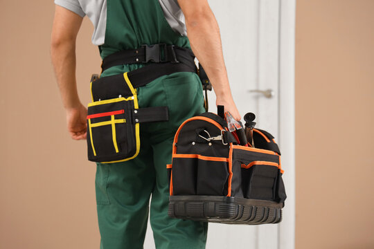 Male worker with tool bag near door at home