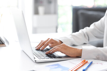 Businesswoman working with laptop at table in office, closeup