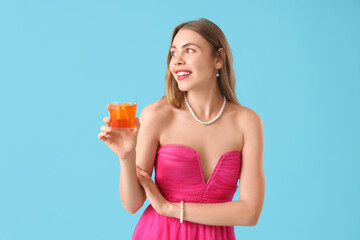Beautiful young woman with aperol spritz cocktail on blue background