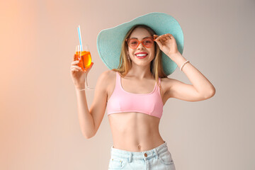 Young woman in sunglasses with aperol spritz cocktail on light background
