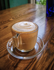 A cup of coffee or cappuccino with foam over wooden table. selective focus.