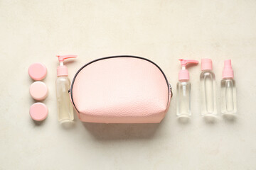 Stylish bag with different travel cosmetic products on light background