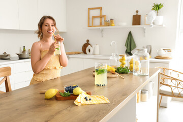 Young woman with tasty lemonade in kitchen