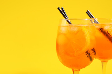 Glasses of Aperol spritz cocktail on yellow background, closeup