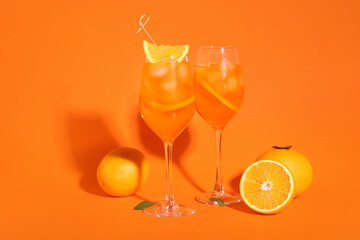 Glasses of Aperol spritz cocktail and fruits on orange background
