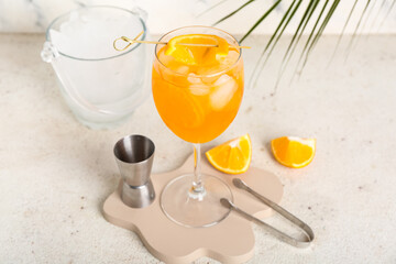 Decorative podium with glass of Aperol spritz cocktail and palm leaf on white background