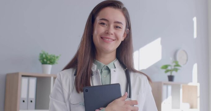 Young beautiful female doctor, specialist in healing or medicine, clinic manager using tablet. Healthcare practitioner making appointment online, choosing treatment, assigning date, reserving meeting