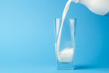 Milk pouring into a glass on a blue background
