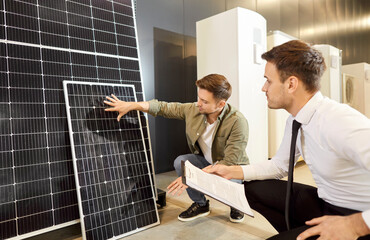 Consultant and client engage in a meeting at a shop, discussing and talking about a solar panels. Alternative energy solutions and environmental sustainability, focusing on solar power.