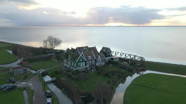Aerial view of serene village, houses, lake, and coast at sunrise, Marken, Netherlands.