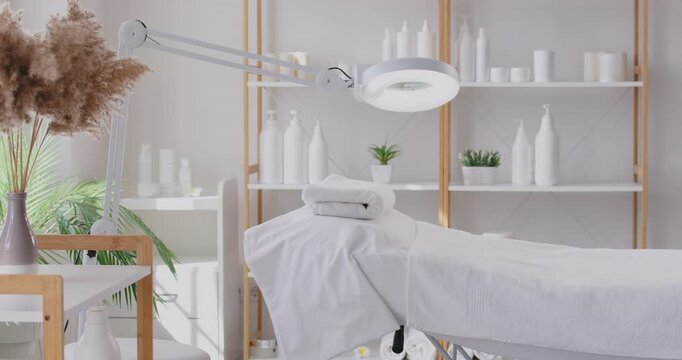Cosmetology salon empty modern cabinet with professional furniture, quality equipment, welcoming atmosphere positive for female clients, medical couch, lamp, serums, creams, masks, and tonics set
