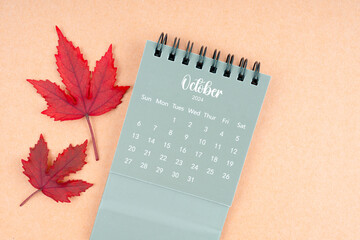 October 2024 monthly calendar and fall leaves on brown.