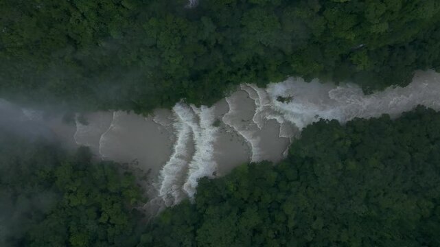 Aerial view of lush rainforest with pristine waterfall and winding river, Semuc Champey, Guatemala.