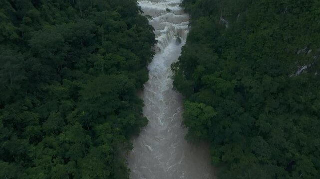 Aerial view of lush and remote rainforest with cascading waterfall and winding river, Semuc Champey, Guatemala.