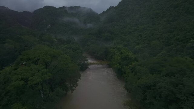Aerial view of lush green forest, river, and mountains in misty Semuc Champey, Alta Verapaz, Guatemala.