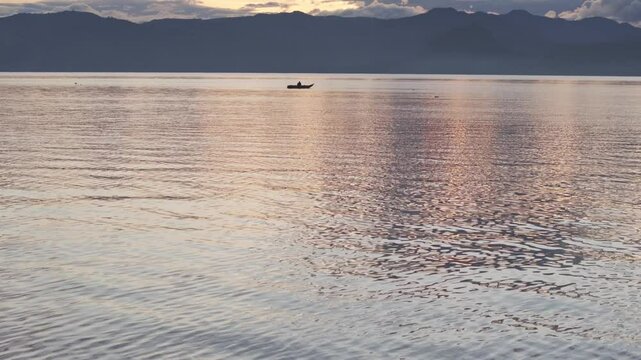 Aerial view of serene Lake Atitlan at sunrise with fishing boats, San Pedro La Laguna, Guatemala.