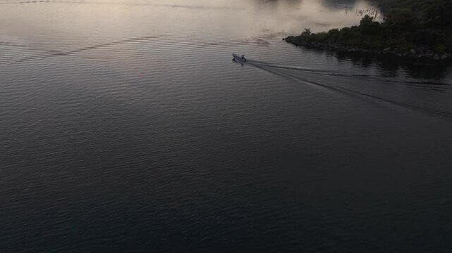 Aerial view of tranquil Lake Atitlan at sunrise with reflection of city and volcanoes, Solola Department, Guatemala.