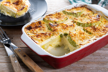 Casserole with cheese and gratin zucchini on wooden table