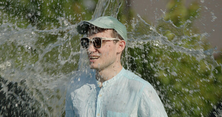 Fototapeta premium Businessman in sunglasses suddenly doused with a bucket of water, concept of surprise and coolness on a hot day
