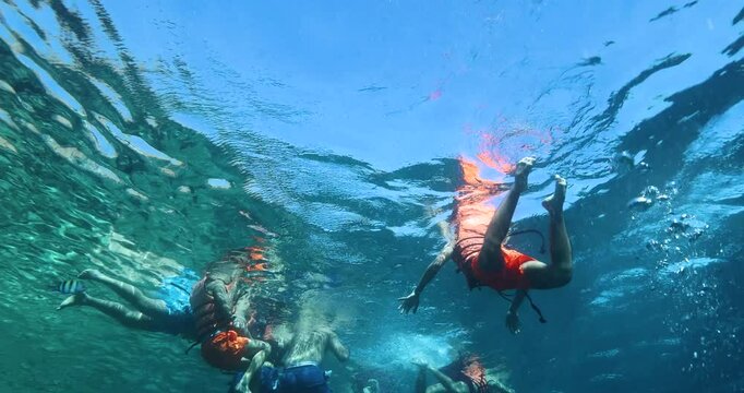 Unrecognizable people swim in life jackets in the azure sea. People in life jackets are being rescued. Tourists snorkel in the sea. Tourism and recreation concept. Underwater footage.