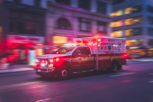 New York, US - May 8, 2023 - Ambulance flashing lights siren blasting speed through midtown rush hour traffic in Manhattan. Motion blur.