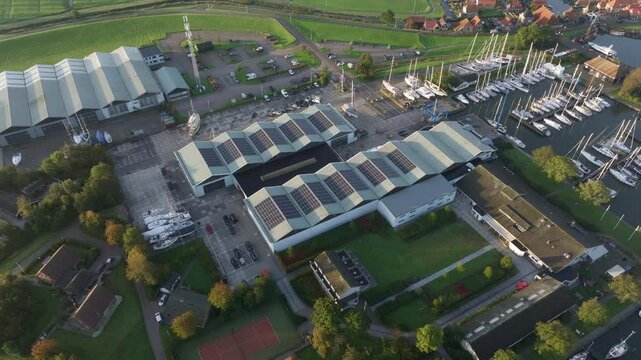 Aerial view of residential buildings, boats, docks, and solar panels by the marina, Hindeloopen, Friesland, Netherlands.