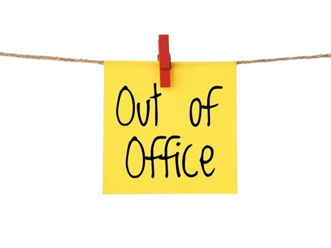 A yellow sticky note with the handwritten text Out of office in black letters. Is it correct: out-of-office message on a paper note