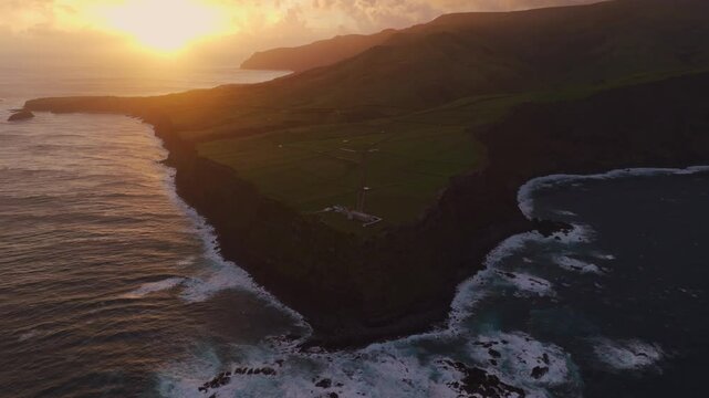 Aerial view of serene sunrise over rocky cliff and ocean, Farol de Albarnaz, Flores, Portugal.