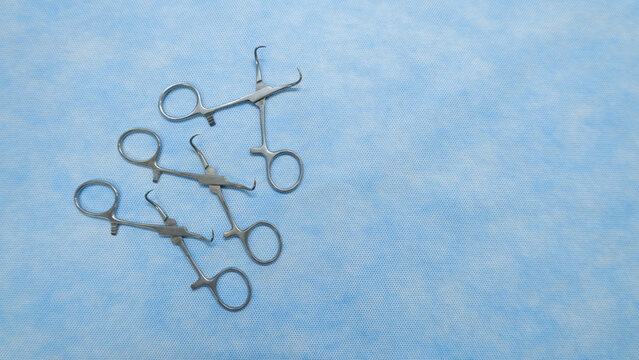Stainless medical towel clamps placed on blue background.Towel clamps are mounting clamps with a pointed end to hold the ends of the towel or doek in place. Medical instrumets used in surgery.