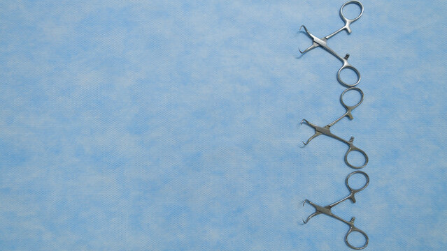 Stainless medical towel clamps placed on blue background.Towel clamps are mounting clamps with a pointed end to hold the ends of the towel or doek in place. Medical instrumets used in surgery.