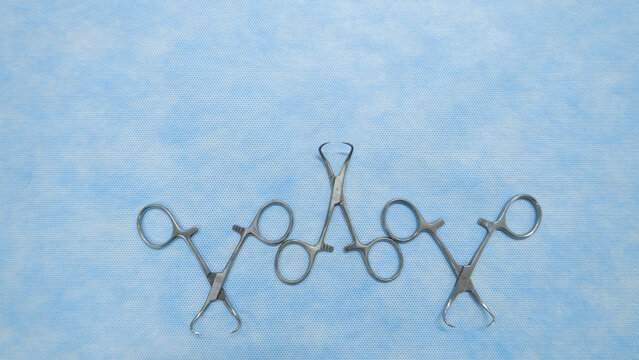 Stainless medical towel clamps placed on blue background.Towel clamps are mounting clamps with a pointed end to hold the ends of the towel or doek in place. Medical instrumets used in surgery.