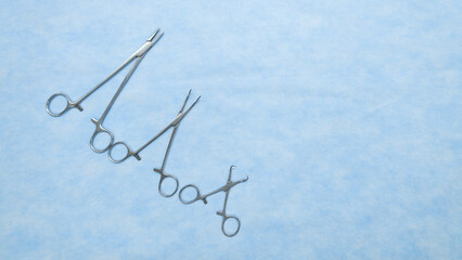 Fototapeta premium Sterile medical scissors used in surgery placed on a blue background. Medical equipment. Surgery instruments.