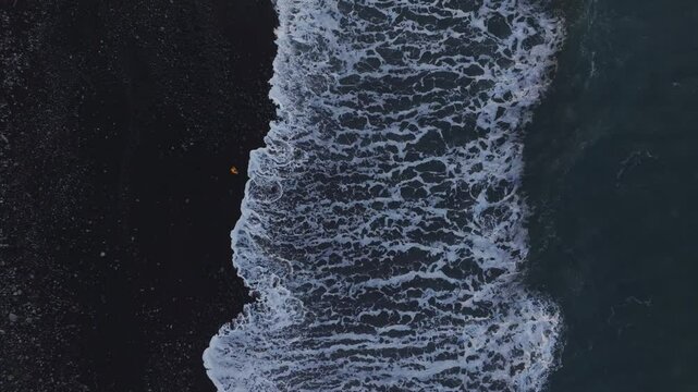 Aerial view of black sand beach with ocean waves at sunrise, Lajes das Flores, Azores, Portugal.