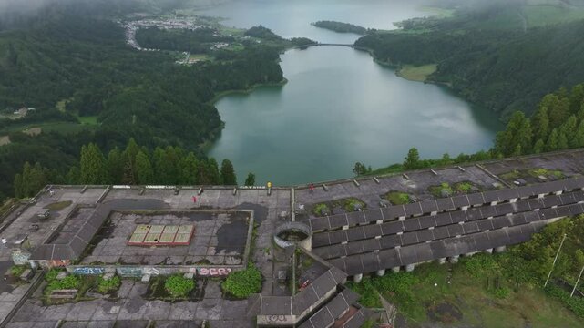 Aerial view of mystical mist over abandoned hotel by serene lake, Sete Cidades, Azores, Portugal.