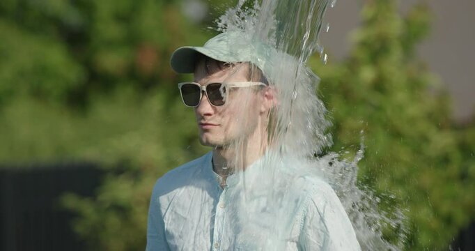 Businessman in sunglasses suddenly doused with a bucket of water, concept of surprise and coolness on a hot day