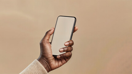 a black hand holding a smartphone with blank screen, beige background