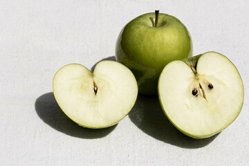Two green apples, one halved, on white background, copy space.