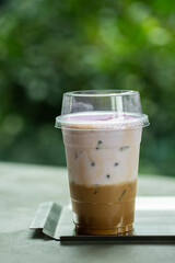 Close up glass of ice coffee with taro milk  on raw cement table of a coffee shop summer terrace, menu photography.