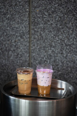 Close up glass of ice coffee with taro milk and ice cappucino  on raw cement table of a coffee shop summer terrace, menu photography.
