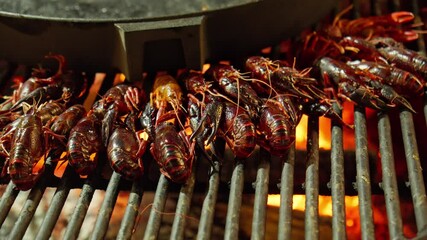 Grill filled with crayfish, sizzling over hot coals. Crayfish cooked to perfect red, and their aroma fills air. Street food concept. Seafood. Summer evening. Bbq. Close-up in 4K, UHD