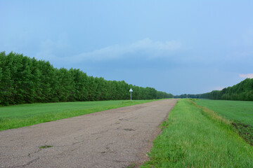 a road with a sign and green grass and forest line copy space