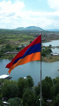  Close view Armenian flag. Drone view Armenian flag on lake  background. Flag near Sevan lake, with mountains background. 