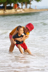 Fototapeta premium Mother holding her child and playing with him on the beach, Mother and child having fun to playing.