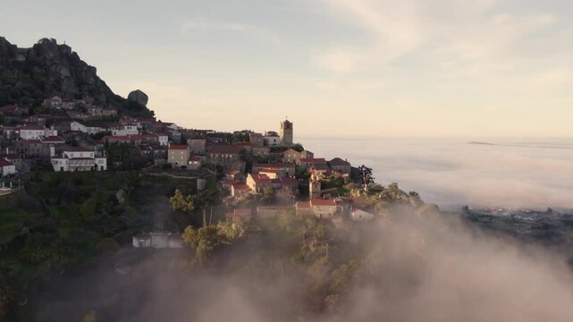 Aerial view of picturesque village with misty mountains and church, Monsanto, Castelo Branco, Portugal.