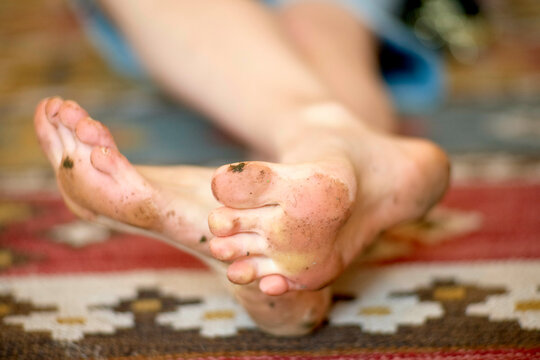 Bare dirty feet of a person resting on a patterned textile surface.
