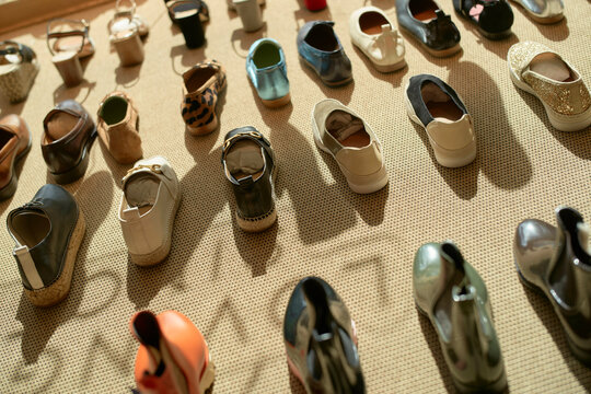 A diverse collection of shoes displayed on a beige background with varying designs and colors.