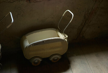An old wicker baby carriage in a dimly lit room.