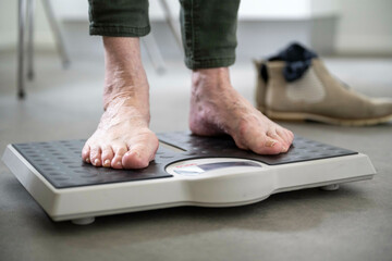 Close-up of a person's bare feet standing on a digital bathroom scale, with one foot on either side of the display, showing weight measurements.