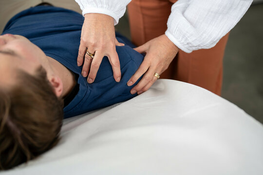 A close-up view of a person receiving a chest physical therapy by a therapist with focus on the hands performing percussive techniques.